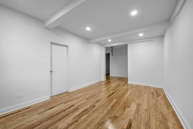 empty room with beamed ceiling and light wood-type flooring