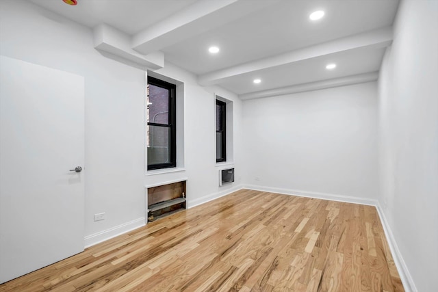 spare room with beam ceiling and light wood-type flooring