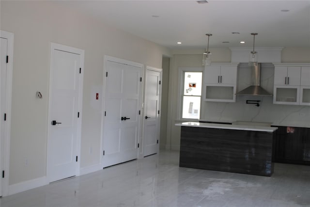 kitchen with decorative backsplash, white cabinetry, wall chimney range hood, and decorative light fixtures