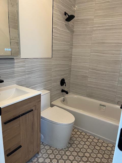 full bathroom featuring vanity, tiled shower / bath combo, toilet, and tile walls