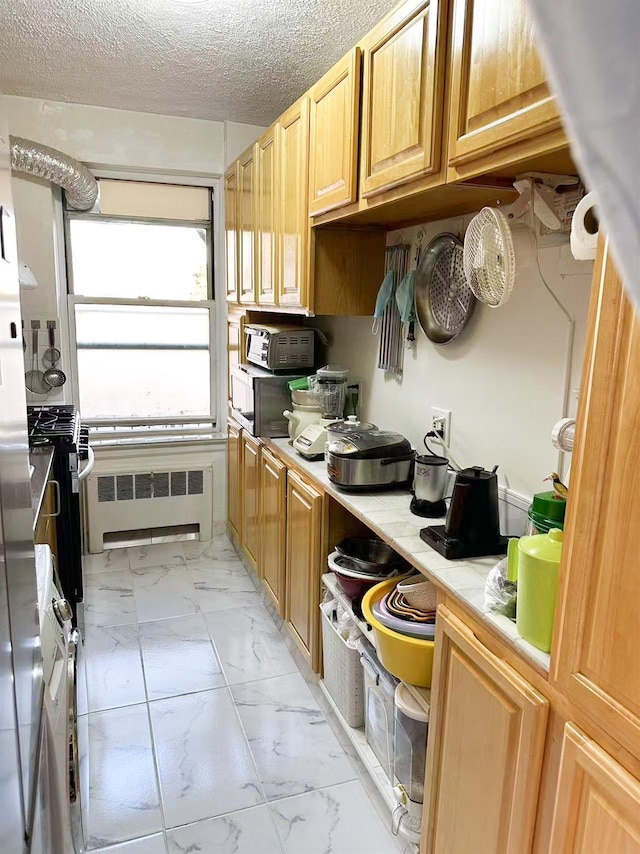 kitchen featuring a textured ceiling, radiator heating unit, and stove