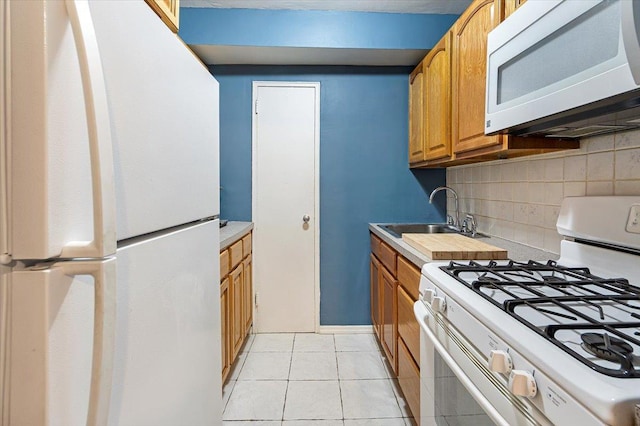 kitchen featuring backsplash, sink, light tile patterned floors, and white appliances