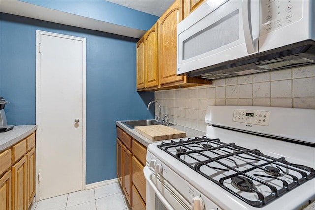 kitchen featuring backsplash, sink, light tile patterned floors, and white appliances