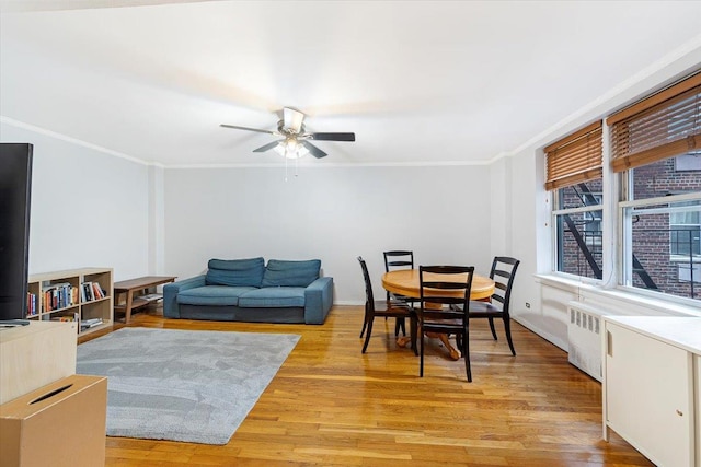 dining space featuring radiator, ceiling fan, light hardwood / wood-style flooring, and ornamental molding