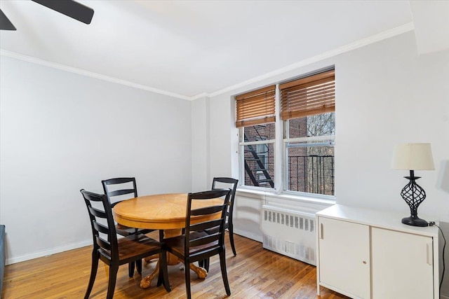 dining room with radiator heating unit, light hardwood / wood-style flooring, and crown molding