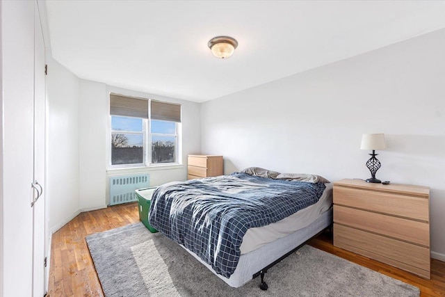 bedroom with radiator heating unit and light hardwood / wood-style flooring