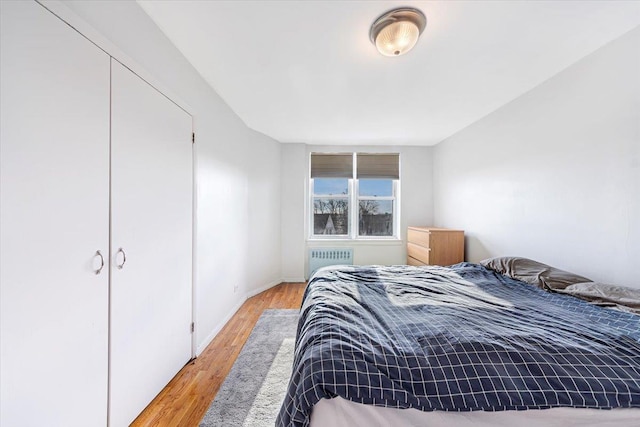 bedroom with radiator, a closet, and light hardwood / wood-style floors