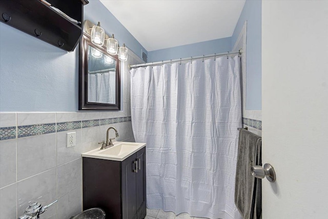 bathroom with vanity, tile walls, and walk in shower