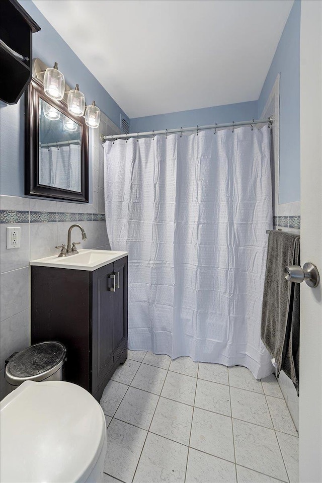 bathroom featuring tile patterned floors, vanity, toilet, and tile walls