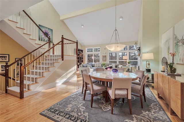 dining space with high vaulted ceiling and hardwood / wood-style floors