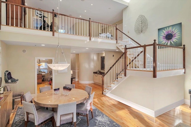 dining room with a towering ceiling and light hardwood / wood-style floors