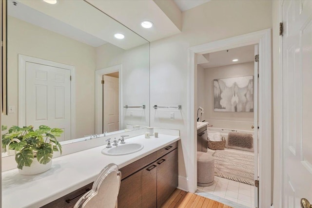 bathroom featuring vanity, a washtub, and wood-type flooring