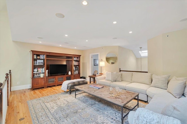 living room with a skylight and light hardwood / wood-style flooring