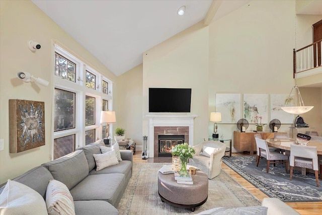 living room featuring a tiled fireplace, hardwood / wood-style floors, and high vaulted ceiling