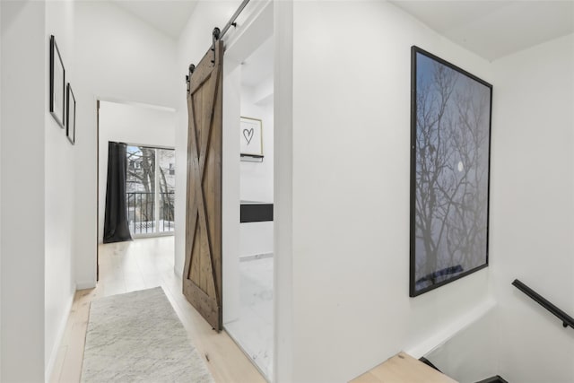 corridor with a barn door and light hardwood / wood-style flooring