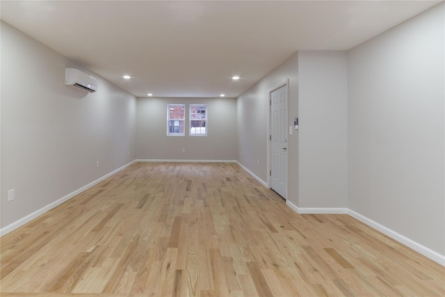 empty room with a wall mounted air conditioner and light wood-type flooring