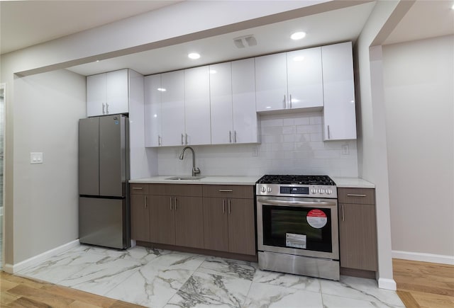 kitchen featuring white cabinetry, dark brown cabinets, sink, and appliances with stainless steel finishes