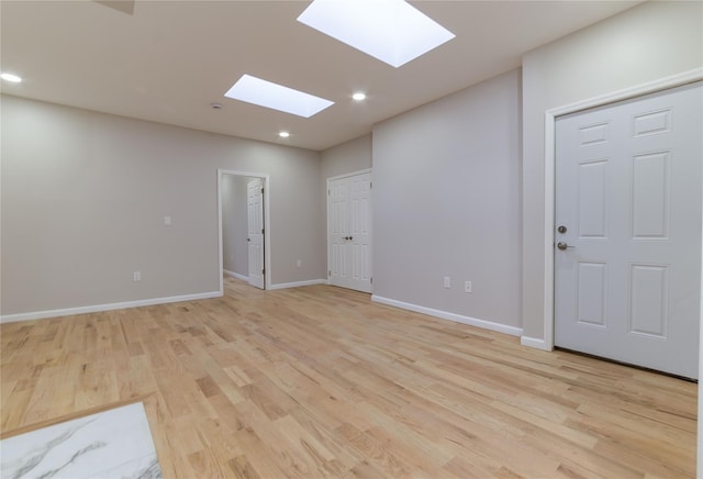 empty room with a skylight and light wood-type flooring