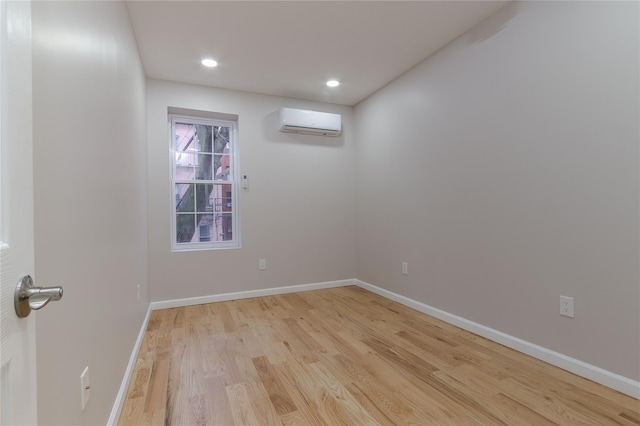 empty room with light hardwood / wood-style floors and an AC wall unit