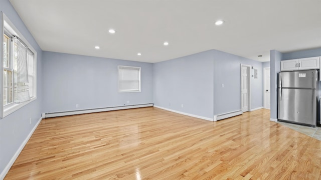 unfurnished living room featuring light hardwood / wood-style flooring and baseboard heating