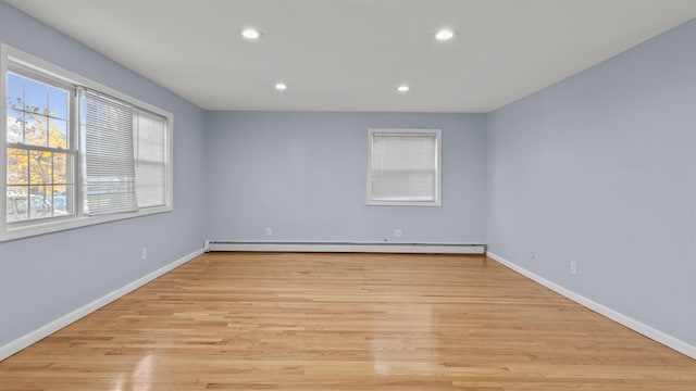 empty room with light hardwood / wood-style floors and a baseboard heating unit