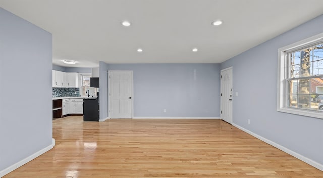 unfurnished living room featuring sink and light hardwood / wood-style floors