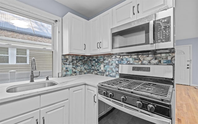 kitchen featuring sink, white cabinetry, light stone counters, decorative backsplash, and stainless steel appliances