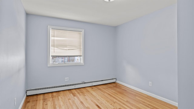 empty room featuring baseboard heating and light hardwood / wood-style flooring