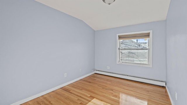 spare room featuring light hardwood / wood-style floors, baseboard heating, and lofted ceiling