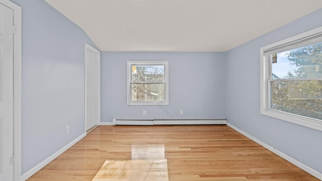 spare room with light hardwood / wood-style flooring, a baseboard radiator, and lofted ceiling