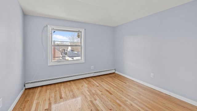 empty room with a baseboard heating unit and light hardwood / wood-style flooring