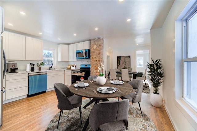 dining space with a wealth of natural light, sink, and light hardwood / wood-style floors