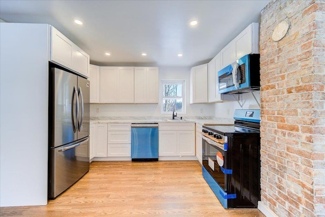 kitchen with sink, light hardwood / wood-style flooring, white cabinets, and appliances with stainless steel finishes