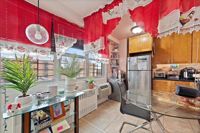 kitchen with an AC wall unit, stainless steel fridge, radiator heating unit, and light tile patterned floors