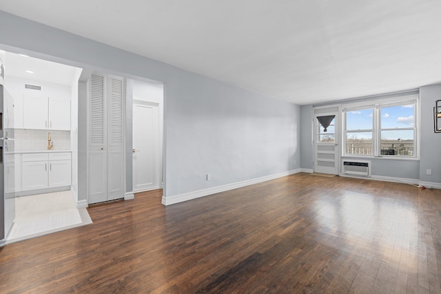 unfurnished living room with dark wood-type flooring and a wall mounted AC