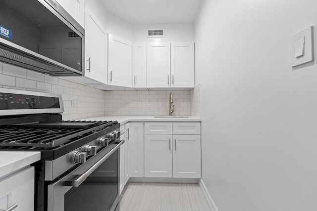 kitchen featuring backsplash, sink, white cabinets, and stainless steel appliances