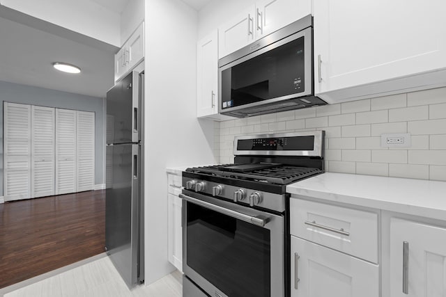 kitchen with white cabinets, appliances with stainless steel finishes, backsplash, and light stone counters