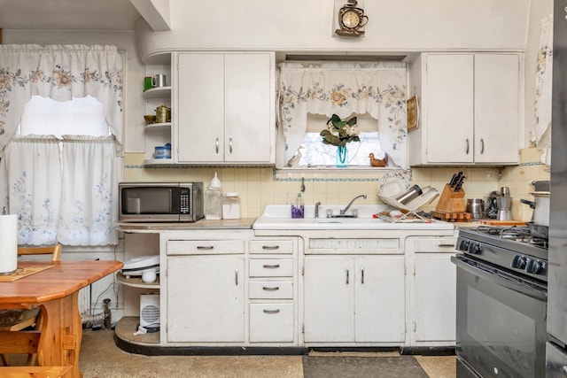 kitchen featuring white cabinets, gas stove, sink, and backsplash