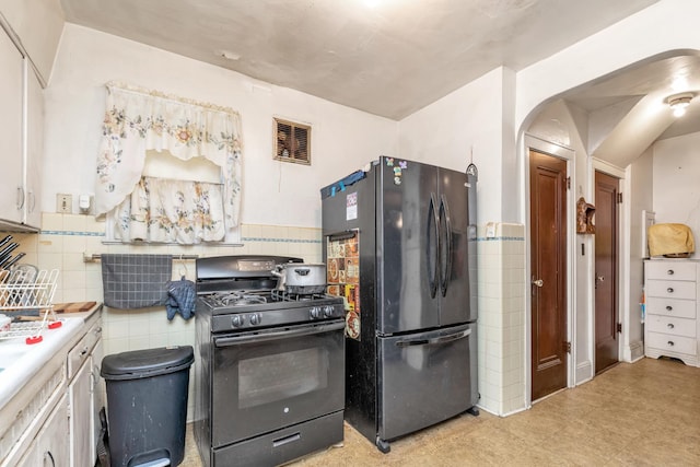 kitchen featuring white cabinetry, black appliances, and tile walls