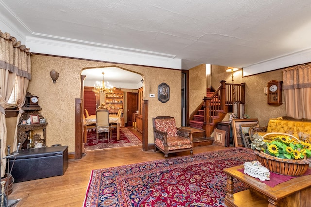 living room featuring an inviting chandelier, light hardwood / wood-style floors, a textured ceiling, and ornamental molding