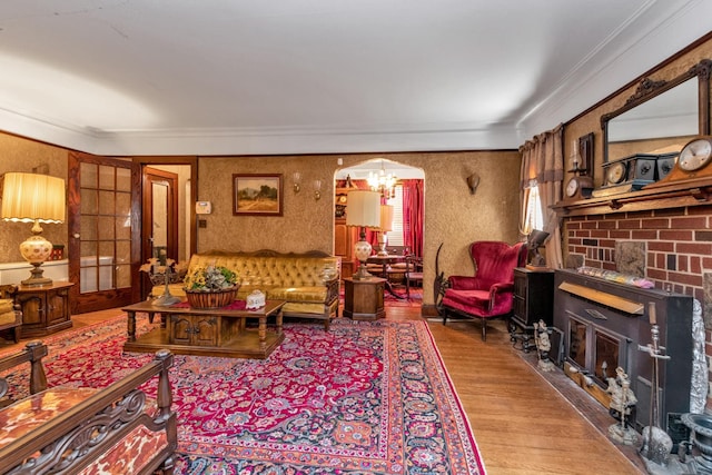 living room featuring wood-type flooring, ornamental molding, and a fireplace