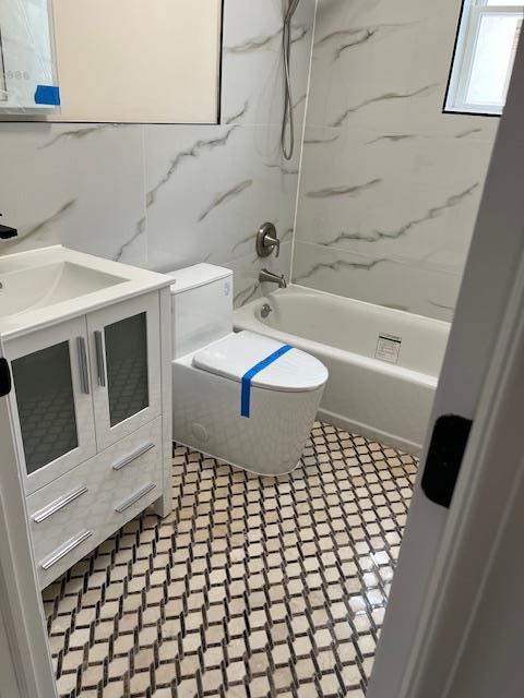 bathroom with vanity, tile walls, and tiled shower / bath