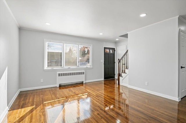 foyer with radiator heating unit, hardwood / wood-style flooring, and ornamental molding