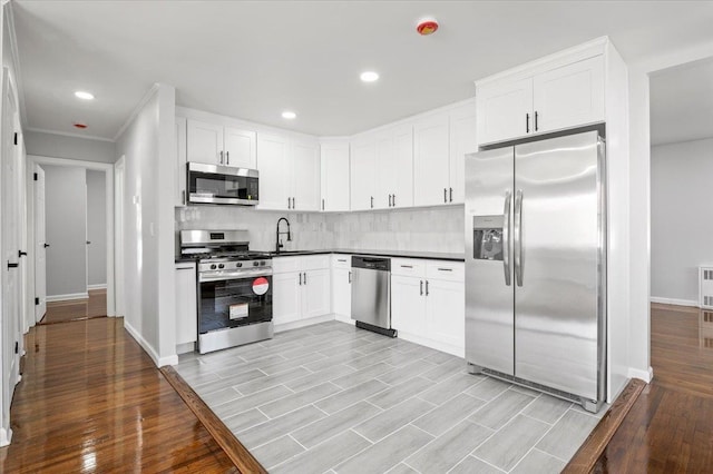 kitchen with white cabinets, sink, tasteful backsplash, light hardwood / wood-style floors, and stainless steel appliances