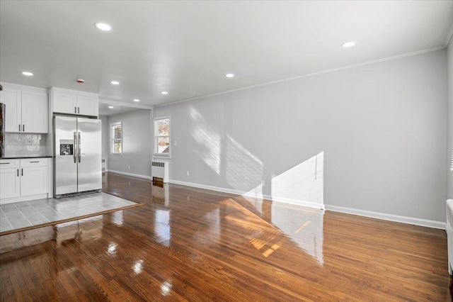 unfurnished living room featuring radiator heating unit, ornamental molding, and wood-type flooring