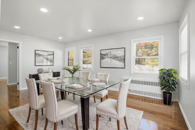 dining room with a healthy amount of sunlight, dark hardwood / wood-style flooring, and radiator