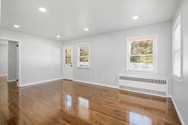 empty room featuring radiator heating unit and dark hardwood / wood-style floors