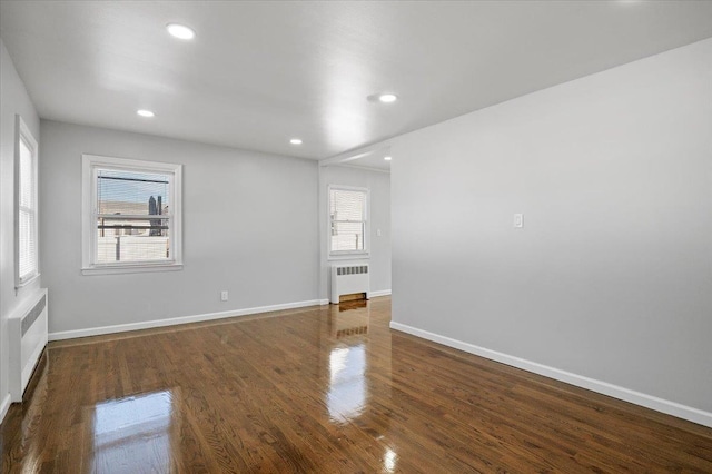 spare room featuring dark hardwood / wood-style flooring and radiator heating unit