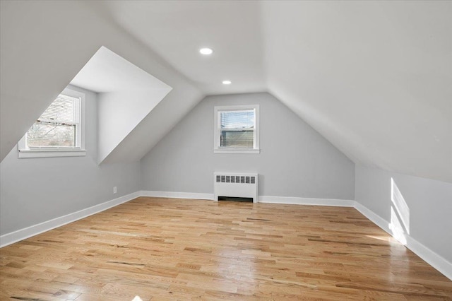 bonus room with lofted ceiling, light wood-type flooring, and radiator heating unit