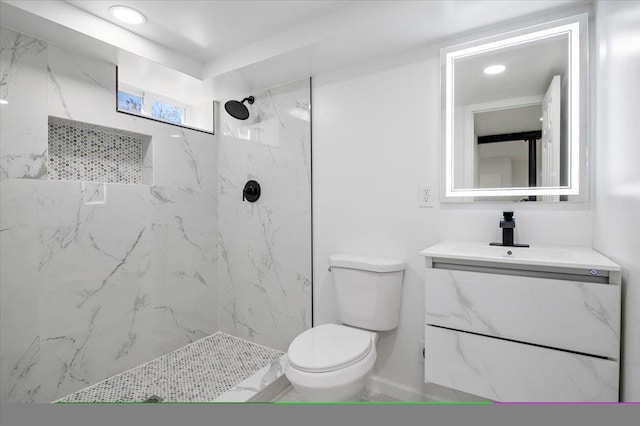 bathroom featuring vanity, toilet, and a tile shower